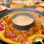 Hot pot ao estilo Sichuan com caldo apimentado, pimentas vermelhas e acompanhamentos
