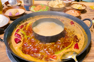 Hot pot ao estilo Sichuan com caldo apimentado, pimentas vermelhas e acompanhamentos