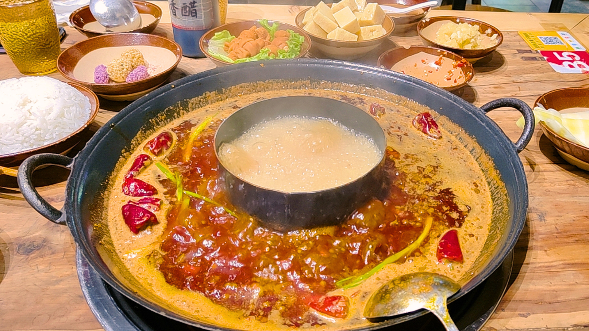 Hot pot ao estilo Sichuan com caldo apimentado, pimentas vermelhas e acompanhamentos