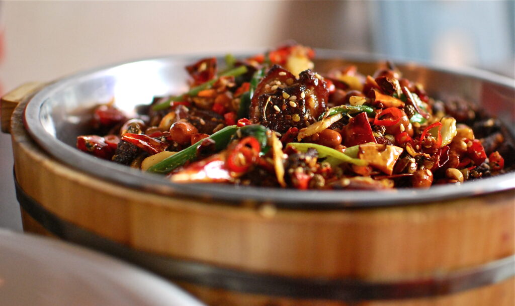 Prato da culinária de Sichuan com frango, amendoim e pimentas vermelhas